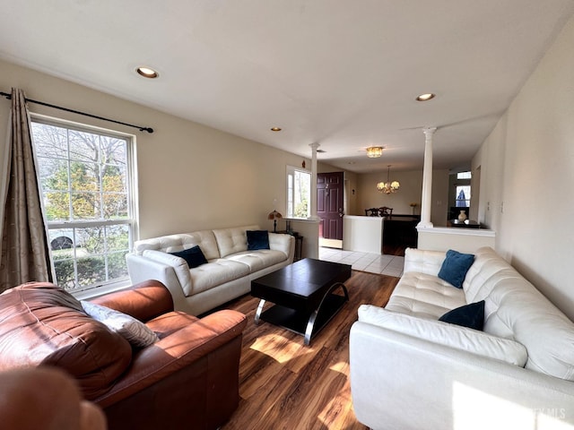 living room with decorative columns, recessed lighting, wood finished floors, and a notable chandelier