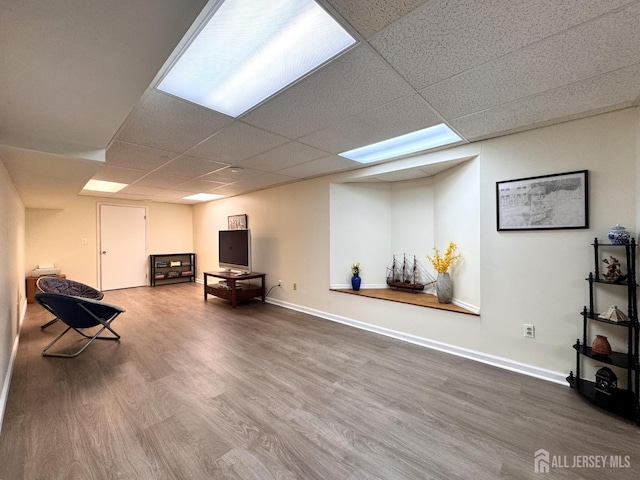sitting room with baseboards, a drop ceiling, and wood finished floors