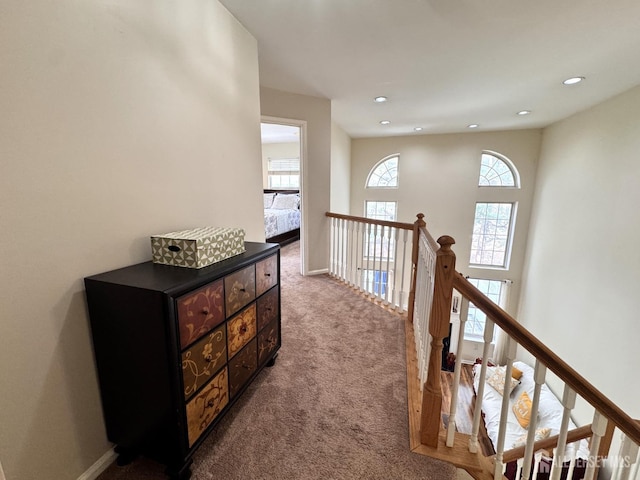 hallway with recessed lighting, baseboards, an upstairs landing, and dark colored carpet