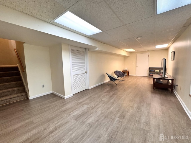 interior space with baseboards, a drop ceiling, and wood finished floors
