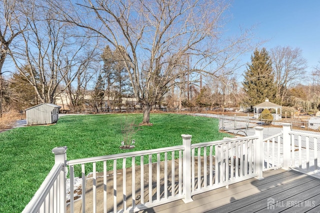 wooden deck featuring a gazebo, a storage unit, and a lawn