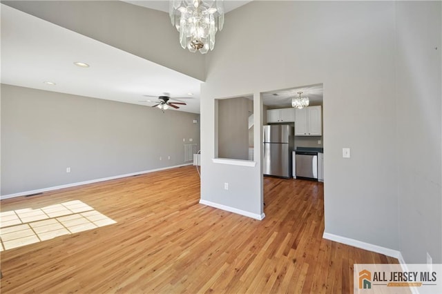 21 Capica Ct Unit 89, South Amboy, NJ 08879 - unfurnished living room with a chandelier, ceiling fan, light wood finished floors, a towering ceiling, and recessed lighting