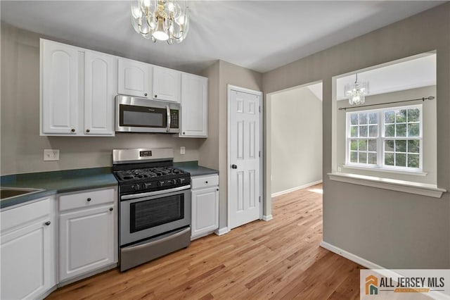 21 Capica Ct Unit 89, South Amboy, NJ 08879 - kitchen featuring stainless steel appliances, a chandelier, dark countertops, and light wood-style floors