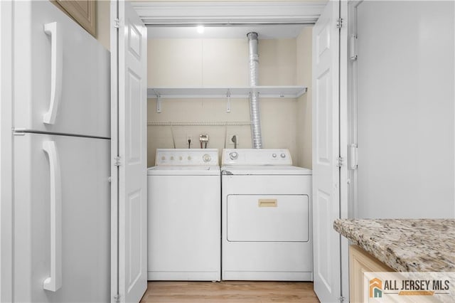 washroom with laundry area, light wood-type flooring, and washer and clothes dryer