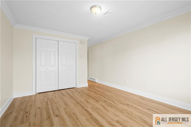 unfurnished bedroom with ornamental molding, light wood-style flooring, a textured ceiling, and visible vents