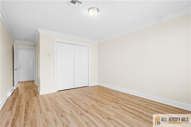 unfurnished bedroom with a textured ceiling, visible vents, crown molding, light wood-type flooring, and baseboards