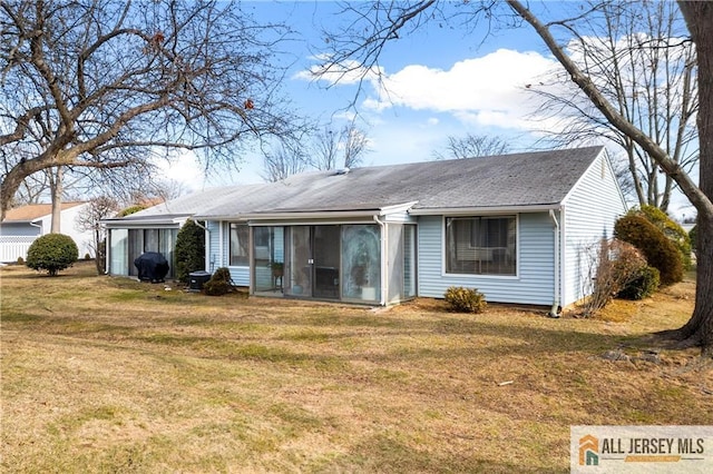 view of front of house with a front yard, a shingled roof, and a sunroom