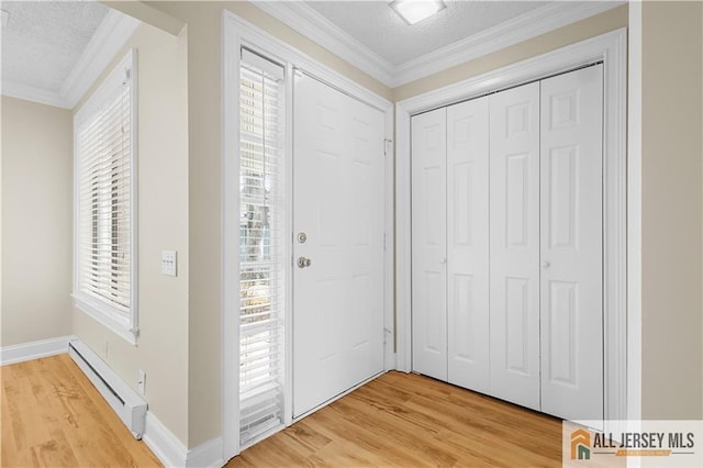entryway featuring crown molding, a textured ceiling, light wood-style flooring, and a baseboard radiator