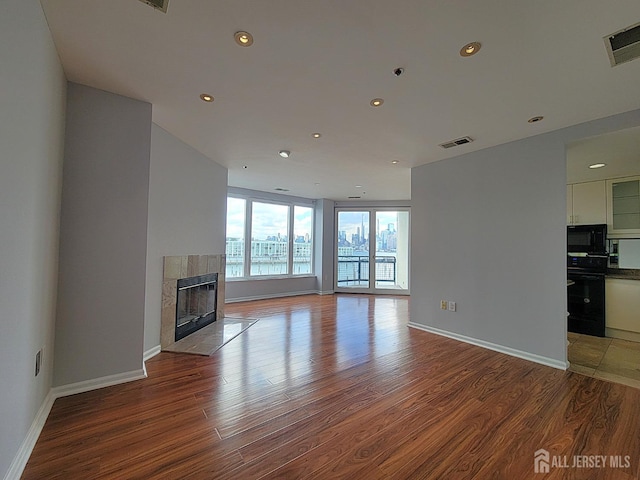 unfurnished living room featuring hardwood / wood-style floors and a tiled fireplace