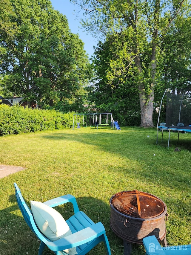 539 Locust Ave, Garwood, NJ 07027 - view of grassy yard featuring a trampoline, a playground, and an outdoor fire pit