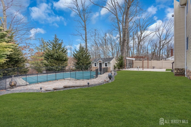 view of swimming pool with a patio, a fenced backyard, a yard, an outdoor structure, and a fenced in pool