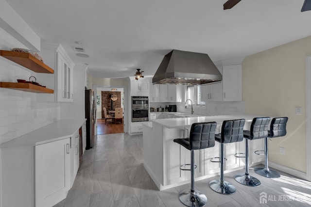 kitchen with extractor fan, a breakfast bar area, a peninsula, and light countertops