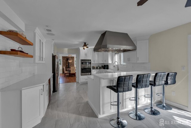 896 Kearney Dr, North Brunswick, NJ 08902 - kitchen with a peninsula, a kitchen bar, ventilation hood, light countertops, and appliances with stainless steel finishes