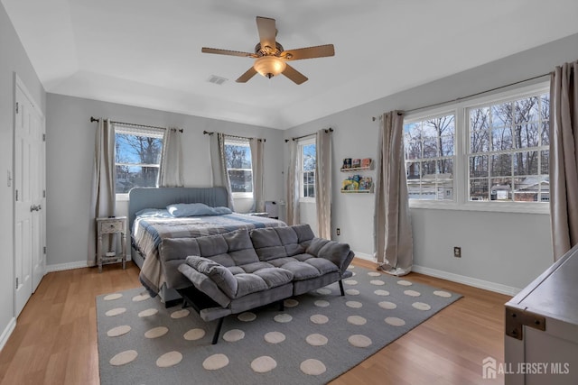 bedroom with light wood finished floors, visible vents, a ceiling fan, and baseboards