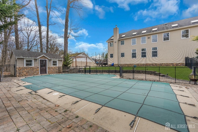 view of swimming pool with an outbuilding, a fenced in pool, a patio, and fence