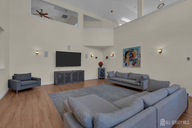 living room with visible vents, high vaulted ceiling, wood finished floors, baseboards, and ceiling fan