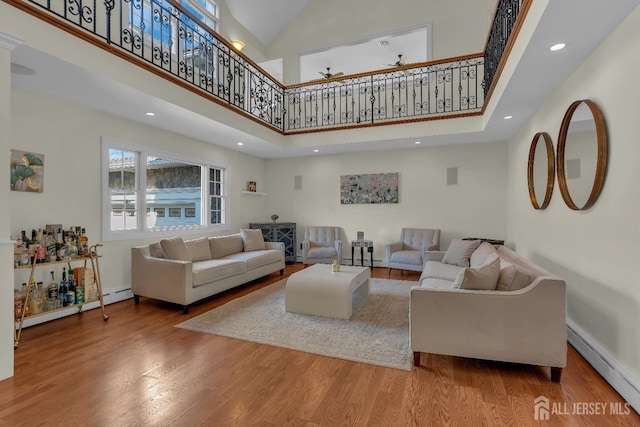 living room with recessed lighting, wood finished floors, baseboards, and baseboard heating