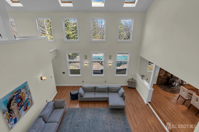 living room with a skylight, wood finished floors, and a high ceiling