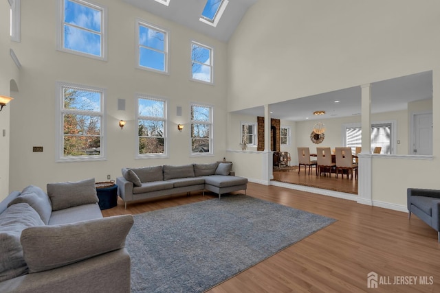 living area with arched walkways, baseboards, and wood finished floors