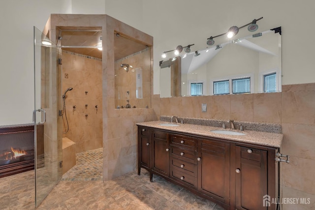 bathroom with a sink, tile walls, and a shower stall