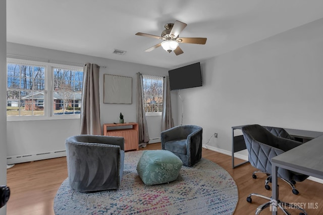 home office with baseboards, wood finished floors, ceiling fan, and a baseboard radiator