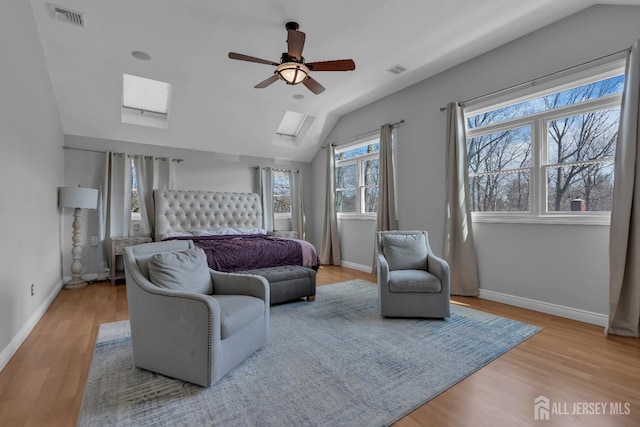 bedroom with vaulted ceiling with skylight, wood finished floors, and visible vents