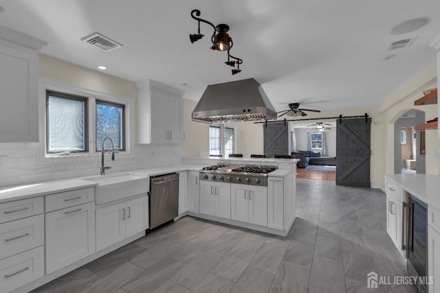 kitchen featuring ventilation hood, visible vents, a sink, stainless steel appliances, and a barn door