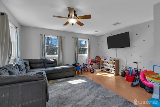 living area with a ceiling fan, wood finished floors, and visible vents