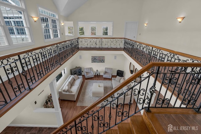 staircase featuring wood finished floors and high vaulted ceiling