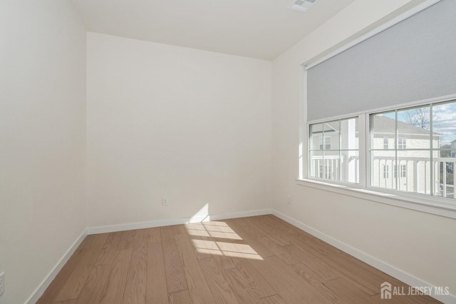 empty room featuring light wood-type flooring, visible vents, and baseboards