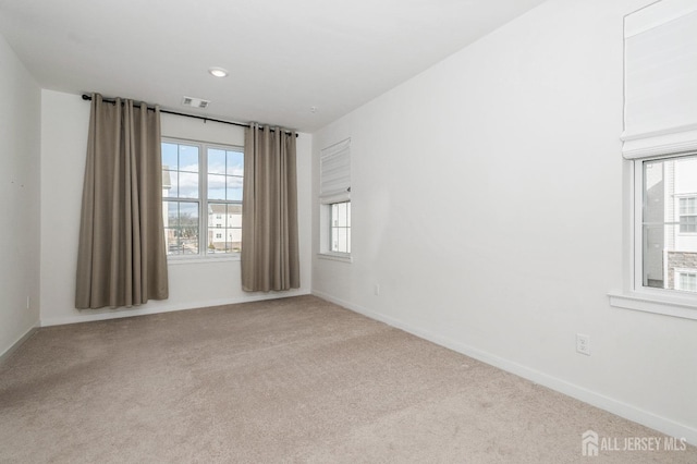 spare room featuring light carpet, baseboards, and visible vents