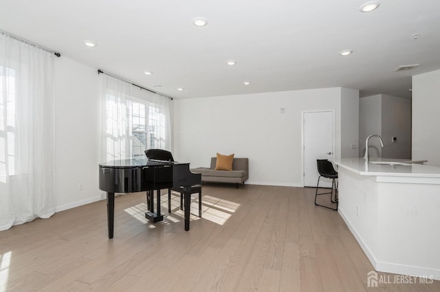 office area with light wood-type flooring, baseboards, a sink, and recessed lighting