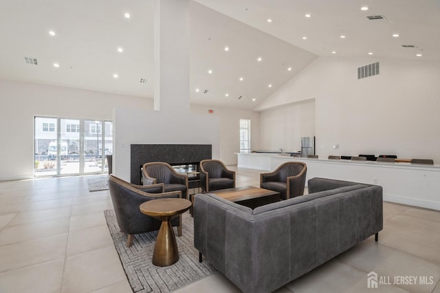 living area with high vaulted ceiling, a premium fireplace, and visible vents