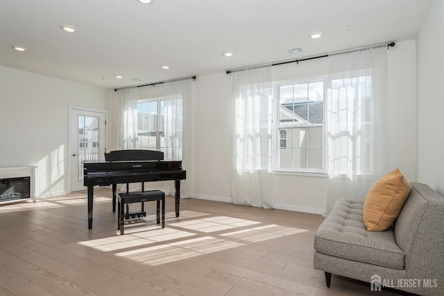 sitting room featuring light wood-style floors, visible vents, a glass covered fireplace, and recessed lighting