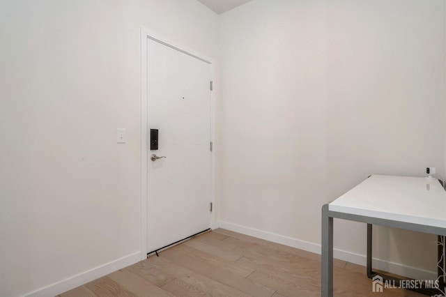 laundry room with light wood-type flooring and baseboards