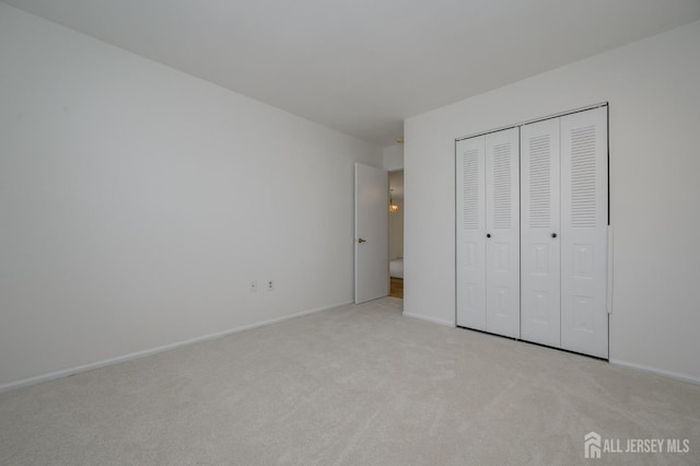 unfurnished bedroom featuring a closet, light carpet, and baseboards