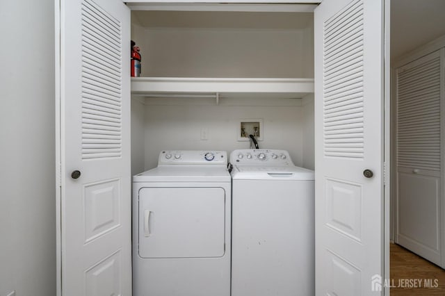 clothes washing area with wood finished floors, laundry area, and washing machine and clothes dryer