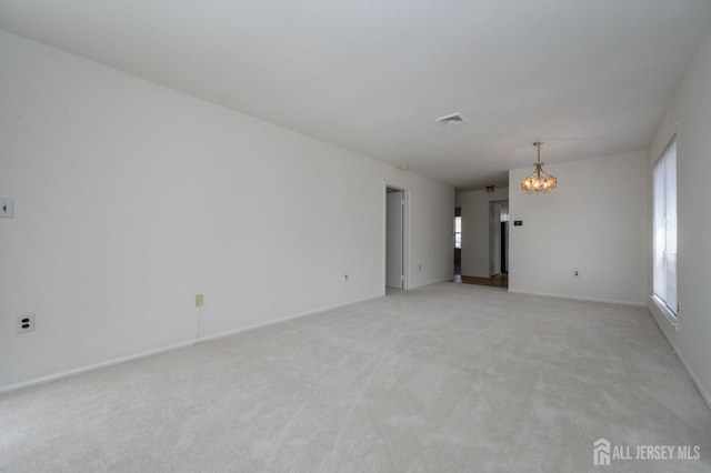 unfurnished room with visible vents, light colored carpet, an inviting chandelier, and a healthy amount of sunlight