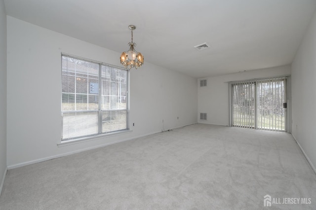 carpeted empty room with a chandelier, visible vents, and baseboards