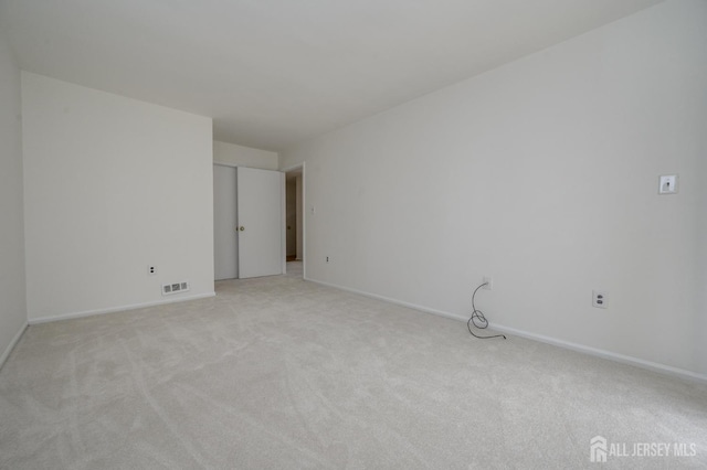 empty room featuring light colored carpet, visible vents, and baseboards