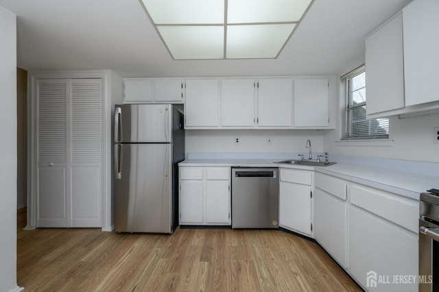 kitchen with light wood-style flooring, a sink, white cabinetry, stainless steel appliances, and light countertops