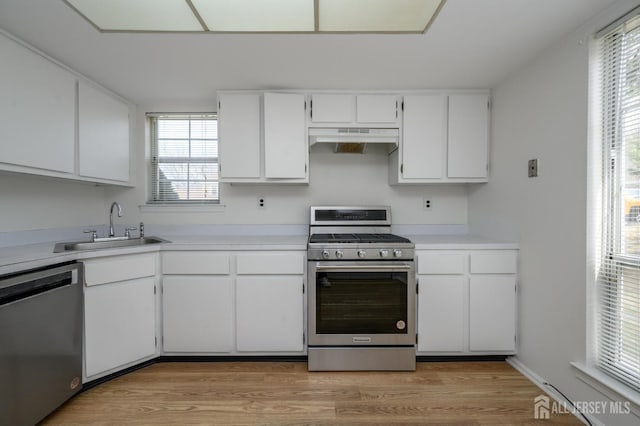 kitchen with under cabinet range hood, light wood-style flooring, appliances with stainless steel finishes, plenty of natural light, and a sink