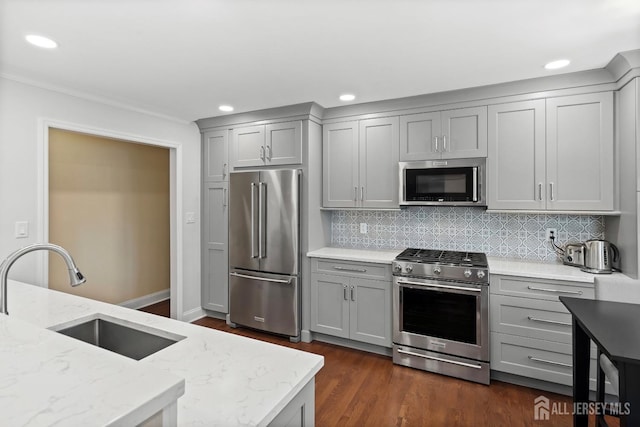 kitchen featuring appliances with stainless steel finishes, dark wood-type flooring, light stone counters, gray cabinets, and sink