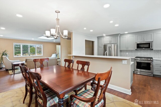 dining area with light wood-type flooring and an inviting chandelier