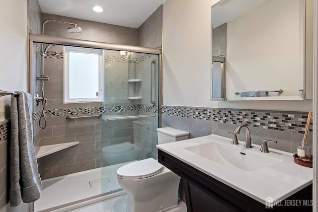 bathroom featuring tile walls, vanity, toilet, and a shower with shower door