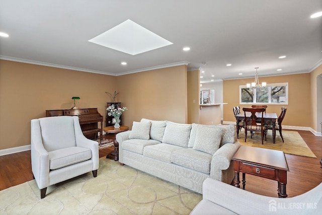 living room featuring a notable chandelier, light hardwood / wood-style flooring, a skylight, and ornamental molding