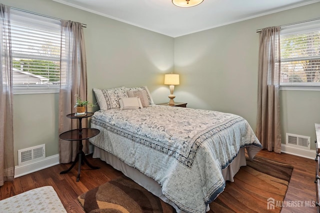 bedroom with ornamental molding and dark hardwood / wood-style floors