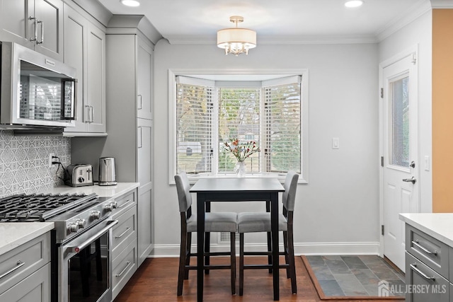 kitchen with gray cabinets, ornamental molding, stainless steel appliances, and backsplash