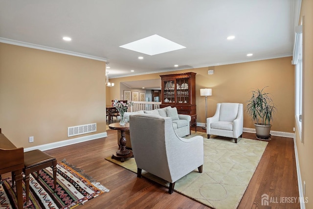 living room with hardwood / wood-style flooring, ornamental molding, and a skylight