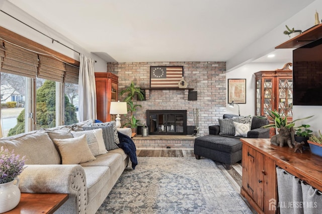 living area featuring a brick fireplace and wood finished floors